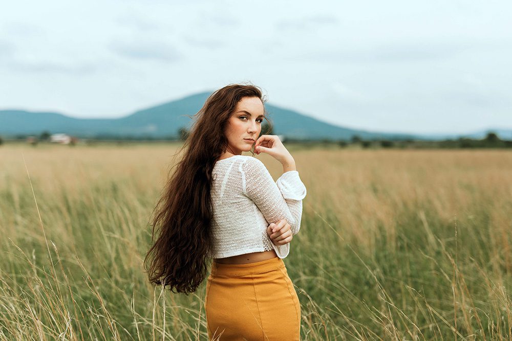 Brunnette woman growing out her hair, standing in a mountainous field
