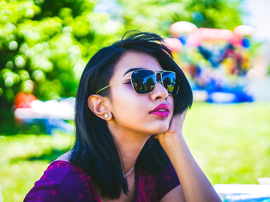 summer hair concept - Young woman with dark hair and sunglasses sits in a park