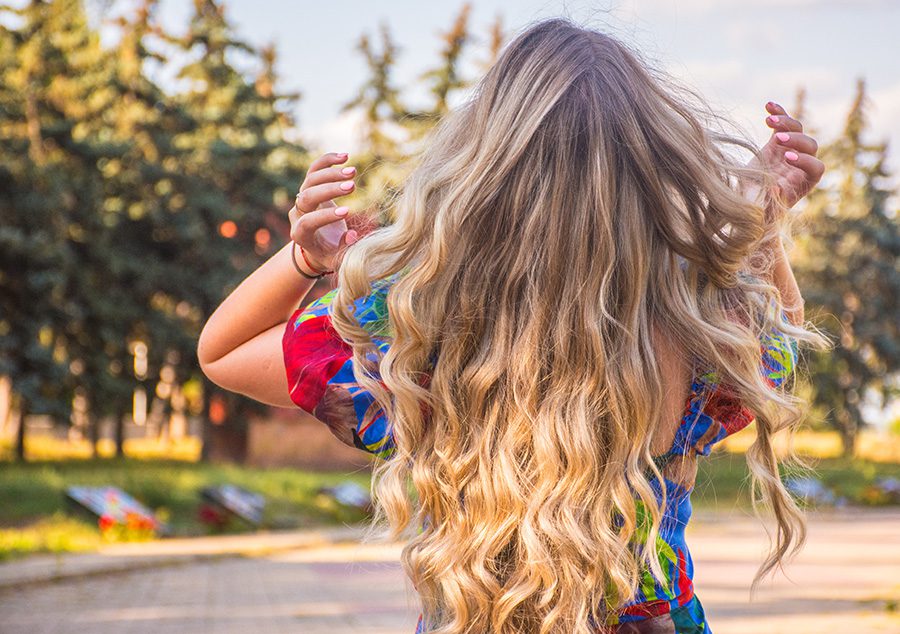 Woman with blonde highlights and hair extensions flipping her hair