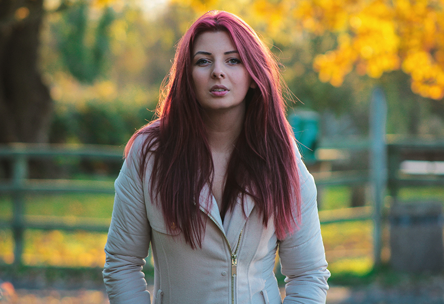 Fall hair trends - young woman with burgandy hair in a park during autumn