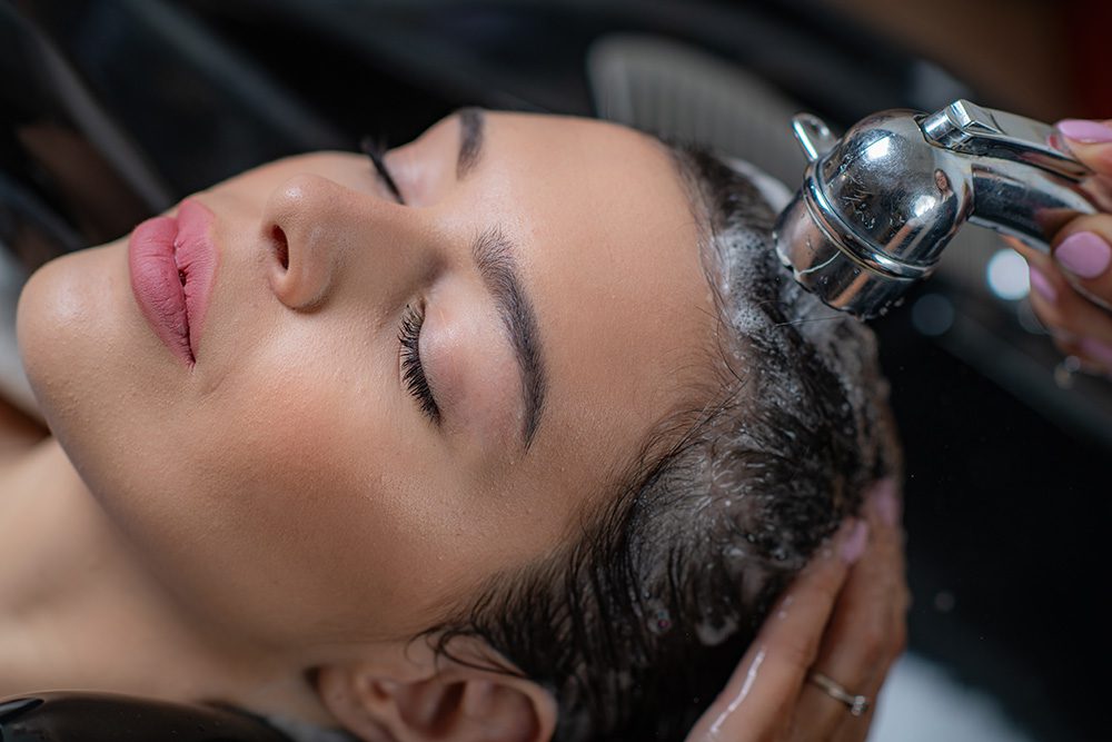 hairdresser washes client's scalp and hair in salon